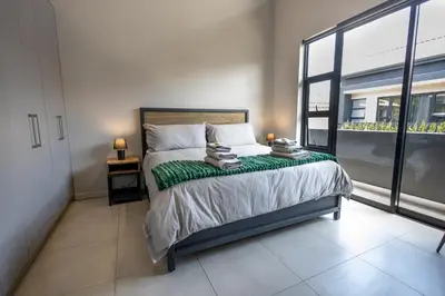 a bedroom with a bed and a large window at Luxurious Upmarket Apartment in Pretoria