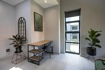 a living room with a table and two plants at Luxurious Upmarket Apartment in Pretoria