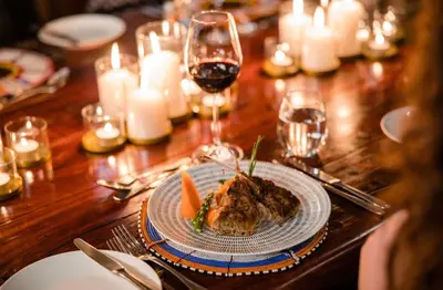 a table with a plate of food and glasses of wine at Makweti Safari Lodge in Welgevonden Game Reserve