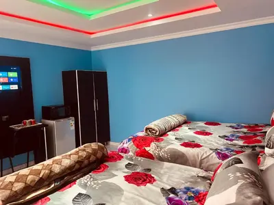 a room with a bed and a blue wall at Goldwell airport Lodge in Kempton Park