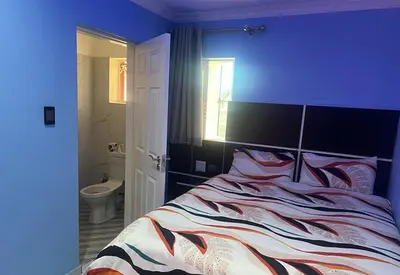 a blue bedroom with a bed and a bathroom at Goldwell airport Lodge in Kempton Park