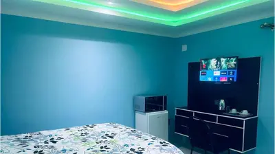 a blue room with a bed and a television at Goldwell airport Lodge in Kempton Park