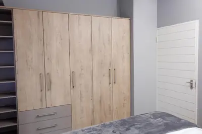 a large wooden cabinet in a bedroom with a bed at Uptown Apartments - Garden Pavillion in Nelspruit