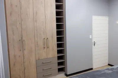 a bedroom with a wooden closet with shelves at Uptown Apartments - Garden Pavillion in Nelspruit