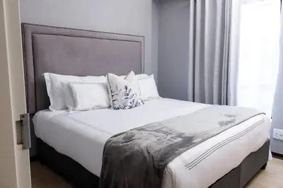 a bedroom with a large bed with white pillows at Uptown Apartments - Garden Pavillion in Nelspruit
