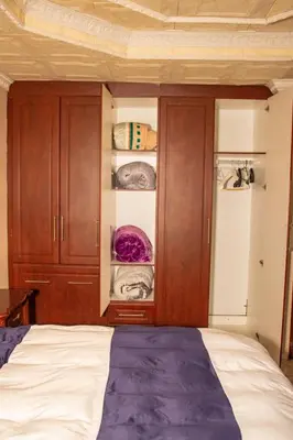 a bedroom with a bed and some wooden cabinets at Lizpeter guest house in Elim