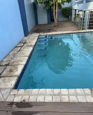a swimming pool next to a building at Lizpeter guest house in Elim