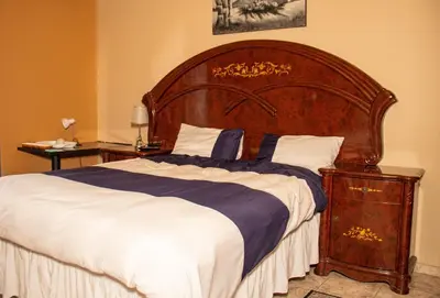 a large bed with a wooden headboard in a bedroom at Lizpeter guest house in Elim