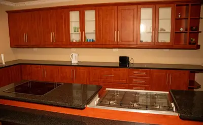 a kitchen with wooden cabinets and a black counter top at Lizpeter guest house in Elim