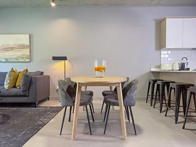 a living room with a table with chairs and a kitchen at Seed @Colette in Pretoria