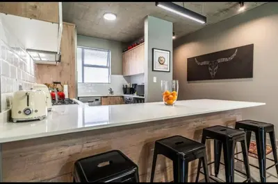 a kitchen with a counter with stools and a counter top at Seed @Colette in Pretoria