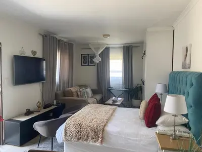 a bedroom with a bed and a couch and a tv at Mamuka Africa in Midrand