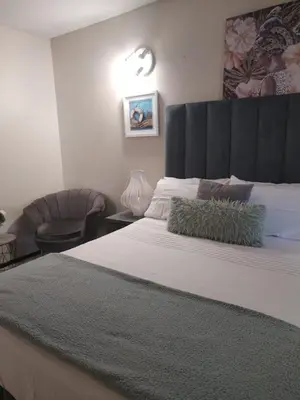 a bedroom with a large bed and a chair at Wampi guesthouse in Polokwane