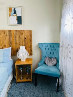 a bedroom with a blue chair next to a bed at Wampi guesthouse in Polokwane