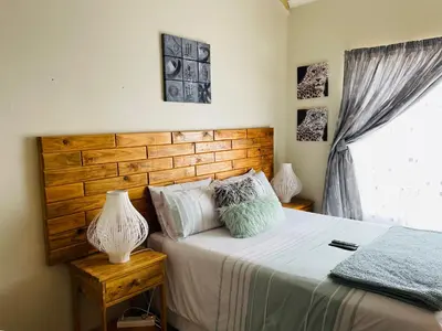 a bedroom with a bed with a wooden headboard and a window at Wampi guesthouse in Polokwane