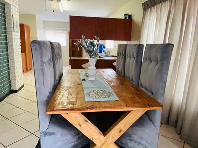 a wooden table with chairs and a vase of flowers on it at Wampi guesthouse in Polokwane