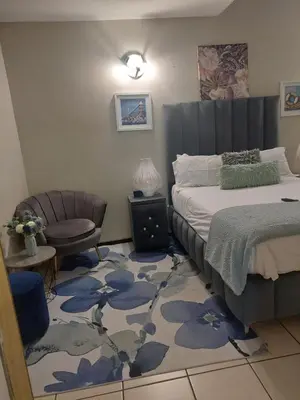 a bedroom with a bed and a chair at Wampi guesthouse in Polokwane