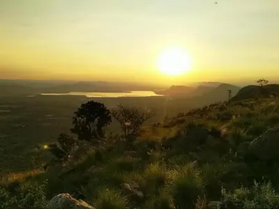 a sunset on the top of a hill with a lake at Bethesda Mountain Lodge in De Wildt