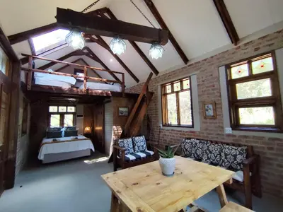 a living room with a table and chairs and a bed at Bethesda Mountain Lodge in De Wildt