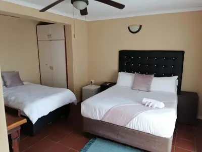 a bedroom with two beds with white sheets and purple pillows at Butterfly tree guesthouse in Phalaborwa