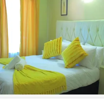 a bedroom with two beds with yellow and white pillows at Butterfly tree guesthouse in Phalaborwa