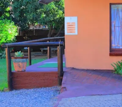 an orange building with a sign on the side of it at Butterfly tree guesthouse in Phalaborwa