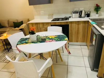 a kitchen with a table and chairs in a kitchen at Nelly`s Green Creek Luxury Apartment in Pretoria
