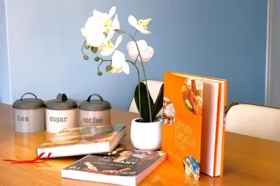 a table with books and a vase with a flower at The Hemingway House 14 Resort Pool in Benoni