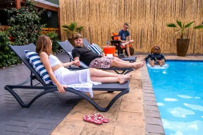 a group of people sitting in chairs by a pool at The Hemingway House 14 Resort Pool in Benoni