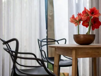 a wooden table with a vase with red flowers on it at Brooklyn Blok in Pretoria