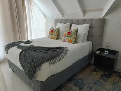 a bedroom with a large bed with pillows and a window at Beautiful apartment behind Illanga Mall in Mataffin