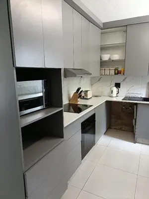 a kitchen with white cabinets and a microwave at Beautiful apartment behind Illanga Mall in Mataffin
