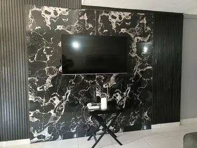 a black and white marble wall with a television on it at Beautiful apartment behind Illanga Mall in Mataffin