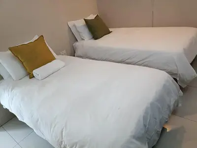 two beds sitting next to each other in a room at Beautiful apartment behind Illanga Mall in Mataffin