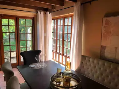 a dining room with a table and two windows at Airbnb at Bailyes in Pretoria