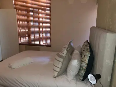 a bedroom with a bed with pillows and a window at Airbnb at Bailyes in Pretoria