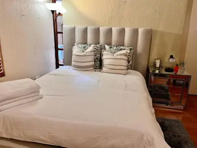 a bed with white sheets and pillows in a bedroom at Airbnb at Bailyes in Pretoria