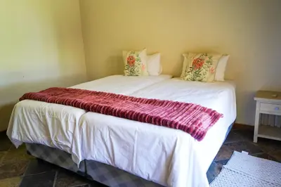 a large white bed with a red blanket on it at Lucca House in Musina