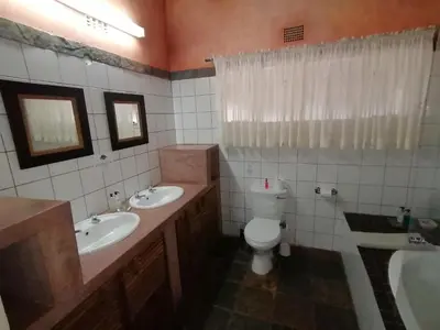 a bathroom with two sinks and a toilet and a tub at Blyde Mountain Country House in Hoedspruit