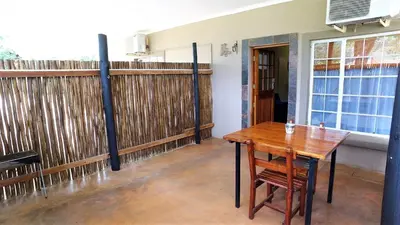 a dining room with a wooden table and a fence at Blyde Mountain Country House in Hoedspruit