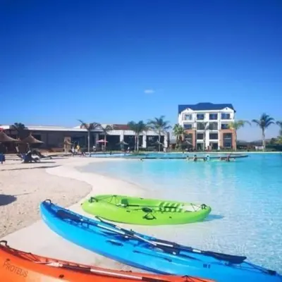 a green boat sitting on a beach next to the water at Kayalako at The Blyde - Blue Crystal Lagoon in Pretoria