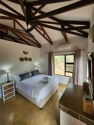 a bedroom with a white bed and a large window at Stella Bush Villa in Hoedspruit