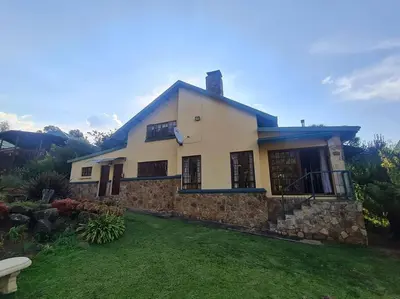 a large white house with a stone wall at Stonefields 3 Bedroom Charmer in Dullstroom