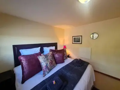 a bedroom with a large bed with purple pillows at Stonefields 3 Bedroom Charmer in Dullstroom