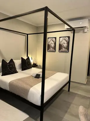 a bedroom with a four poster bed with two pictures at SUumthing Private GuestHouse in Lebowakgomo