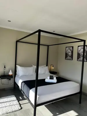a bedroom with a black canopy bed with white pillows at SUumthing Private GuestHouse in Lebowakgomo