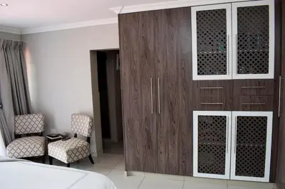 a bedroom with a wooden cabinet and a bed at De Guest @115 in Centurion