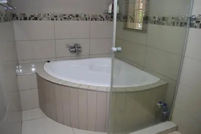 a bathroom with a bath tub with a sink at De Guest @115 in Centurion