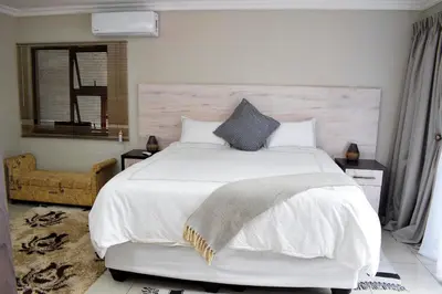 a bedroom with a large white bed and a chair at De Guest @115 in Centurion