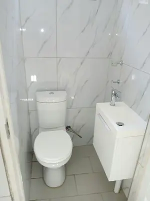 a white bathroom with a toilet and a sink at De Guest @115 in Centurion